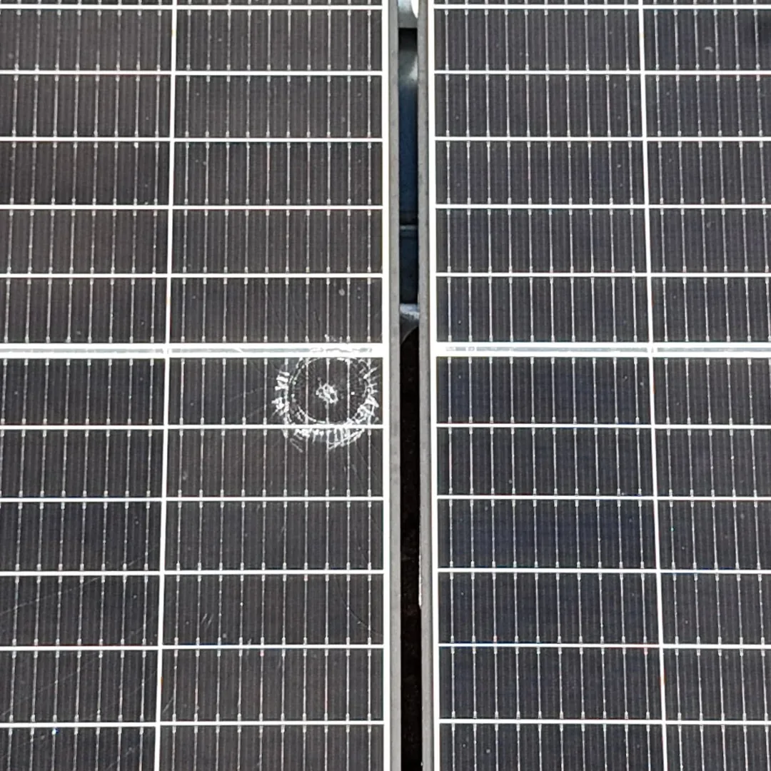 Detail solárneho panela s kruhovou prasklinou v skle