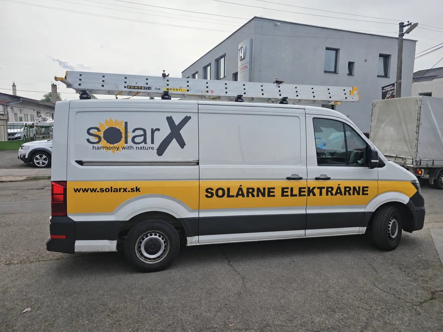 Biela servisná dodávka SolarX s rebríkom na streche
